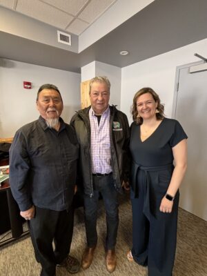 Three people stand inside smiling at the camera.